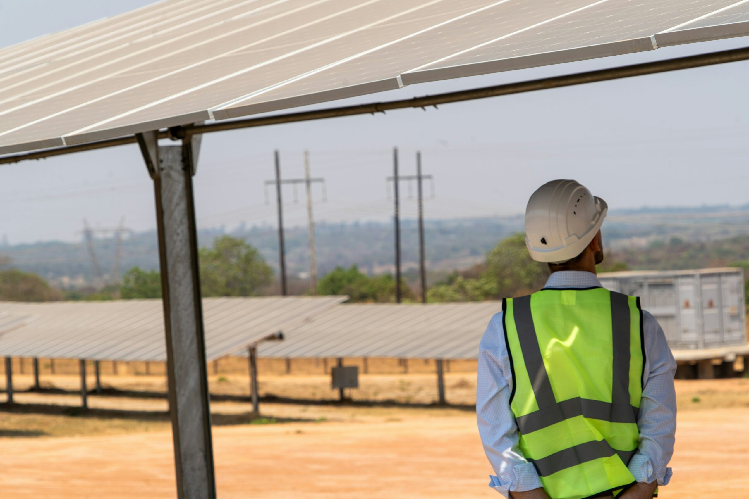 Man with helmet and safety jacket under solar panels